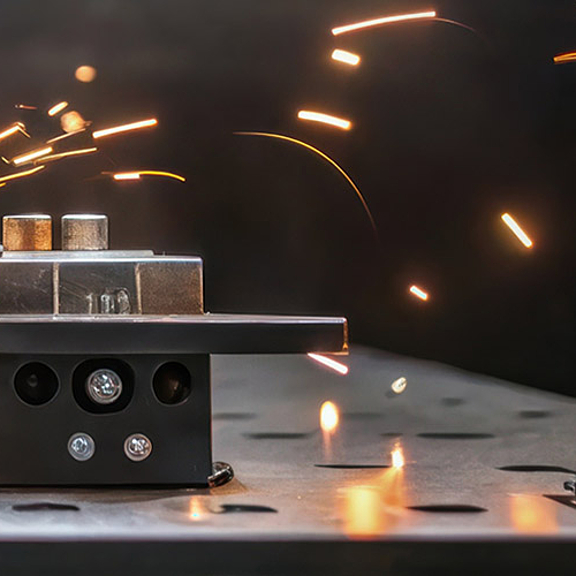 Schweißanlage mit sprühenden Funken. Daneben ein gelbes Gerät.