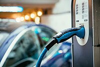 Elektrische Ladesäule mit PKW im Hintergrund