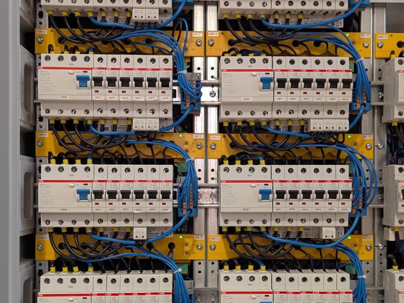 Blick in einen Schaltschrank mit grauen Leistungsschutzschaltern und gelben Bender Differenzstrom-Überwachungsgeräten RCMS150