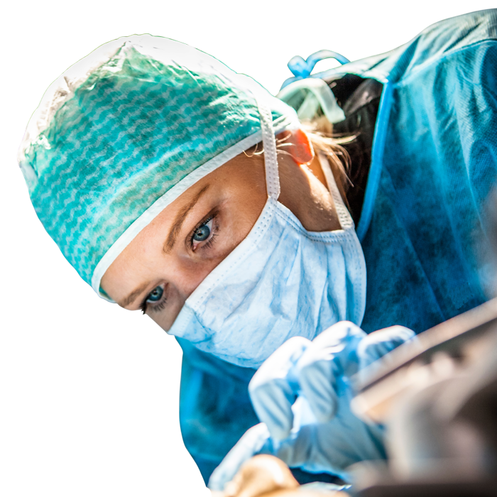 Eine Chirurgin beugt sich über einen OP-Tisch und arbeitet konzentriert