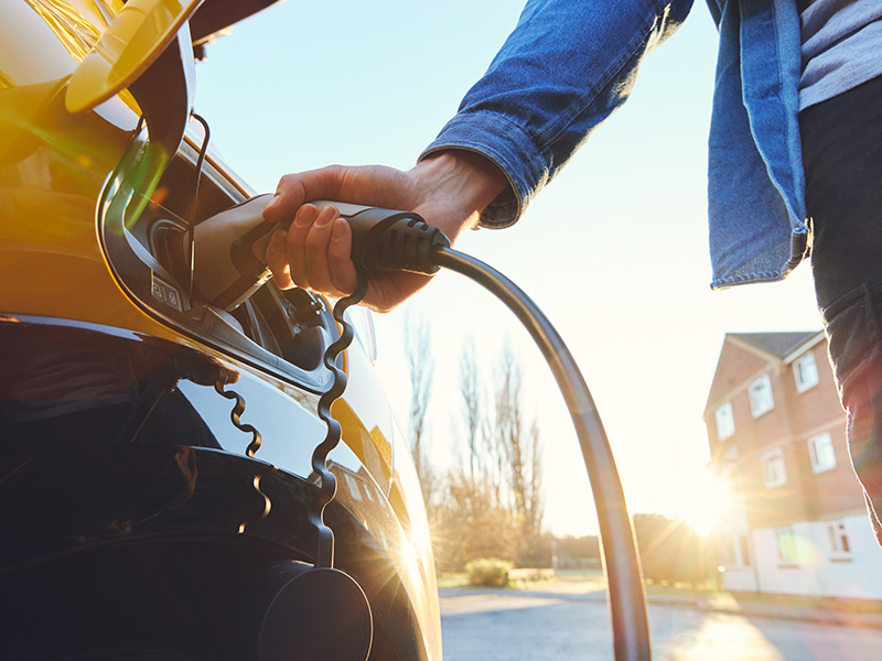 Eine Person steckt einen Ladestecker in ein Elektroauto